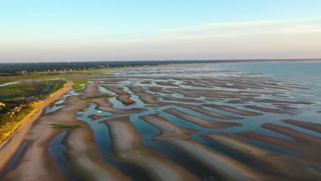 Cape-Cod-Bay-Aerial-Drone-Footage-of-Beach-at-Low-Tide-During-Golden-Hour,-Bright-Sun-Low-and-Setting,-Pan-Right