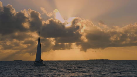 Sailboat-against-brilliant-orange-sunset-near-Isle-of-Pines,-New-Caledonia
