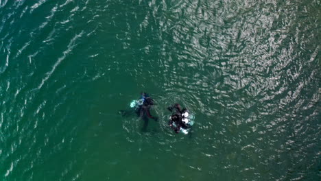 Top-Down-Aerial-Drone-View-of-Scuba-Divers-Emerging-From-Lake-Waters