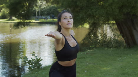 Woman-doing-warrior-and-sun-pose-yoga-exercise-in-beautiful-green-park