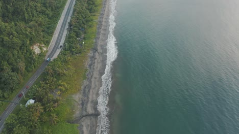 Wellen,-Die-An-Der-Küste-Entlang-Der-Straße-Mit-Fahrzeugen-Spritzen,-Die-Tagsüber-Im-Tropischen-Land-Der-Philippinen-Unterwegs-Sind