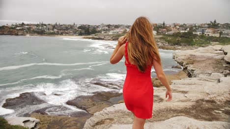 Lovely-Lady-In-Sexy-Red-Dress-Walking-On-The-Rocky-Shore---Eastern-Suburbs-Of-Sydney-In-New-South-Wales,-Australia---full-slowmo-shot