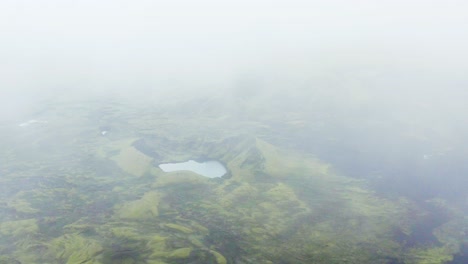 Scenic-View-Of-The-Crater-Of-Tjarnargigur,-Pond-Crater-Surrounded-By-The-Lush-Green-Grass-On-A-Misty-Morning-In-Lakagigar,-Iceland