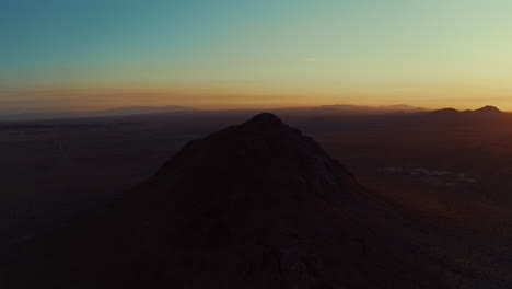 Aerial-orbit-of-a-dormant-volcanic-cone-shaped-mountain-peak-in-the-Mojave-Desert-at-sunrise