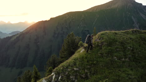 Schöne-Filmische-Luftaufnahme-Eines-Einsamen-Professionellen-Bergwanderers,-Der-Bei-Sonnenaufgang-Auf-Den-Berggipfel-Geht