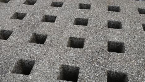 Repeated-geometric-stone-square-holes-carved-in-granite-marble-surface-dolly-right