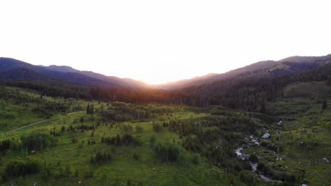 Luftaufnahme-Eines-Wunderschönen-Dunstigen-Sonnenuntergangs-In-Einem-Tal-Des-Grand-Teton-Nationalparks-Mit-Einem-Kleinen-Fluss