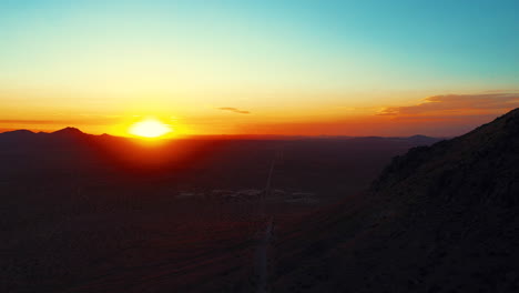 Dawn-breaks-over-the-horizon-in-golden-splendor-as-viewed-from-the-air-in-the-pull-back-shot-over-a-mountain-peak