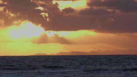 Sunset-through-clouds-over-tropical-ocean-horizon