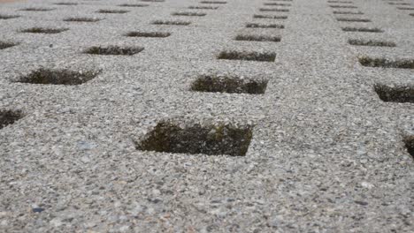 Low-angle-repeated-geometric-stone-square-holes-carved-in-granite-marble-surface-dolly-left