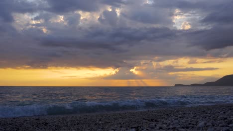 Time-lapse-of-dark-clouds-moving-over-sea-and-beach-at-beautiful-sunset-with-yellow-sky