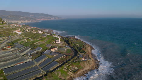 Solar-panel-farm-on-Sanremo-Mediterranean-coast-powering-city,-aerial-view