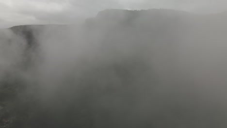 Flying-through-Thick-Fog-Revealing-Beautiful-Green-Mountainous-Landscape-and-a-Lake,-Chic-Chocs-Village,-Gaspesian