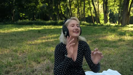 blonde-in-the-park-dancing-listens-to-music-in-headphones