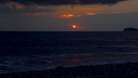 Dark-sea-under-clouds-and-glowing-sky-at-sunset,-dramatic-seascape-on-Ionian-coastline