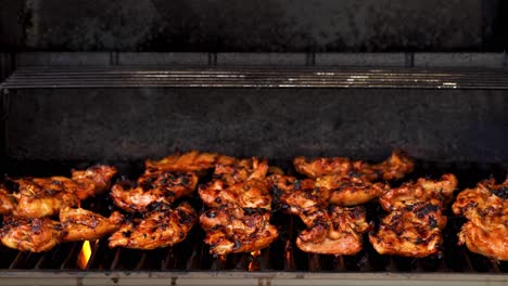 Still-shot-of-BBQ-chicken-cooking-on-a-gas-grill-with-the-hood-open-and-flames-and-smoke-showing