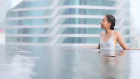 While-looking-out-on-the-city-skyline-a-pretty-young-woman-refreshes-herself-in-a-private-rooftop-pool