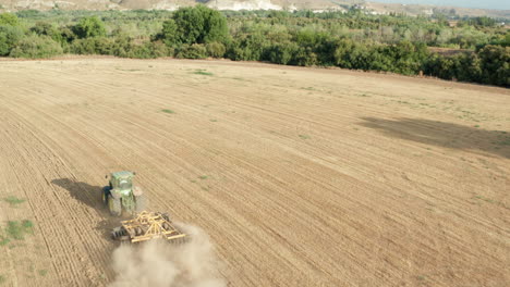 Tractor-Plowing-Farm-Land-for-Harvest-Season-with-Dust-Cloud---Aerial-Flyover