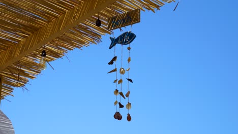 Beach-life-decorations-with-sea-shells-on-straw-roof-of-the-bar-with-clear-blue-sky-background