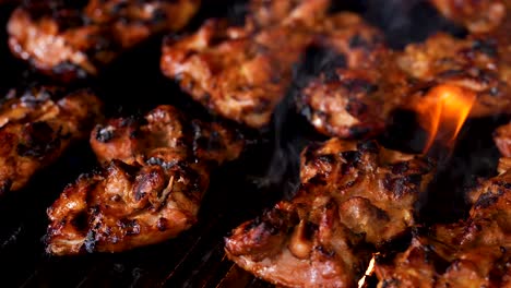Flame-broiled-barbecue-chicken-sizzling-and-grilling-on-a-gas-grill---close-up-panning-shot-to-the-right