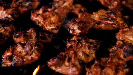 Flame-broiled-barbecue-chicken-sizzling-and-grilling-on-a-gas-grill---close-up-panning-shot-to-the-left