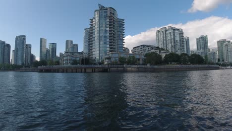 Aerial-Low-fly-by-just-1-feet-above-sea-level-thru-False-Creek-BC-Vancouvers-private-yacht-parking-for-the-elite-few-at-the-most-expensive-housing-building-by-the-water-pier-passing-a-buoy