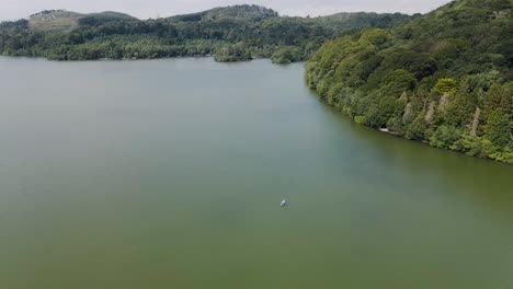 Reversing-and-tilting-aerial-of-couple-relaxing-in-kayak-on-green-lake