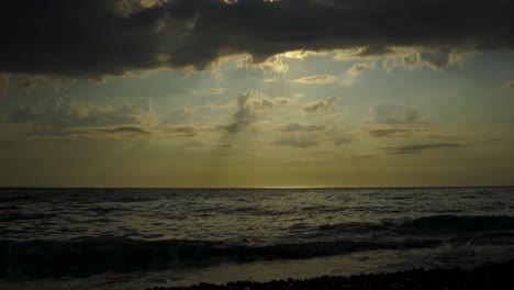 Dramatische-Meereslandschaft-Mit-Dunklen-Wolken,-Die-Den-Sonnenuntergang-Bedecken,-Und-Sonnenstrahlen,-Die-Sich-Auf-Der-Meeresoberfläche-Reflektieren