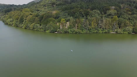 Aerial-view-of-couple-relaxing-in-kayak-on-green-lake-with-forest-in-background