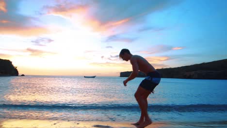 SLOWMO,-Man-doing-side-flip-on-Caribbean-beach-during-stunning-sunset-in-Curacao