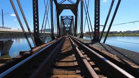 POV-traveling-over-railroad-tracks-while-crossing-a-bridge-over-the-Tempe-Town-Lake,-Tempe,-Arizona
