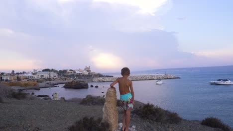 Boy-is-leaning-on-the-rock-and-watching-over-the-shore-of-Spanish-island