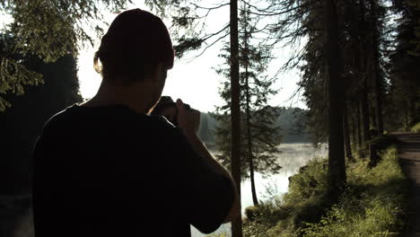 Man-Taking-Photos-Of-Forest-And-Lake-Landscape-In-A-Foggy-Afternoon---medium-shot