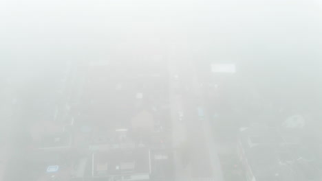 Aerial-of-road-in-suburban-neighbourhood-covered-in-mist