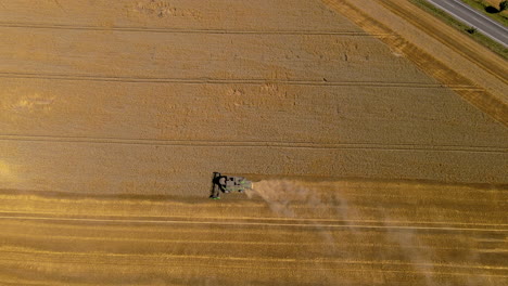 combine-harvester-mows-the-crop-in-the-field,-changing-the-camera-angle-and-view-on-the-horizon,-aerial-footage