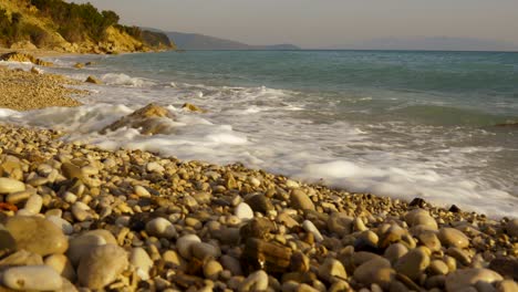 Golden-rocky-beach-with-pebbles-splashed-by-sea-waves-in-Mediterranean-coastline