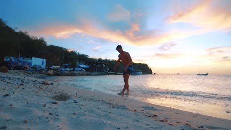 SLOWMO,-Young-man-doing-backflip-on-beach,-colorful-sunset-in-Curacao,-Caribbean