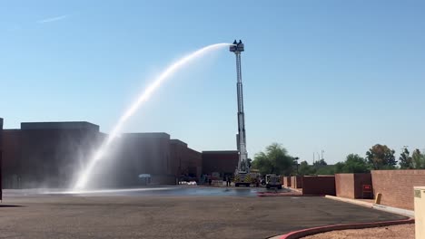 Gallons-of-water-stream-from-the-firehose-of-a-firetruck's-extended-ladder