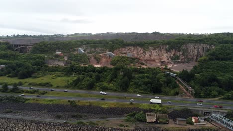 Cemex-mining-site-on-North-Wales-expressway-traffic-aerial-rising-push-in-view-over-construction-site