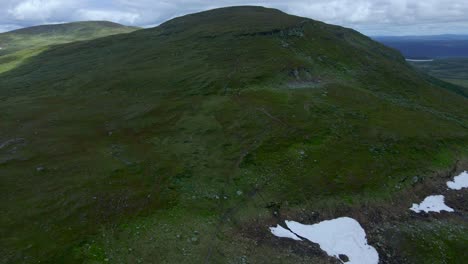 Imágenes-De-Drones-Inversos-Que-Muestran-La-Cima-De-Una-Montaña-Sueca-Con-Excursionistas-Mientras-Revelan-Nieve-En-Medio-Del-Verano