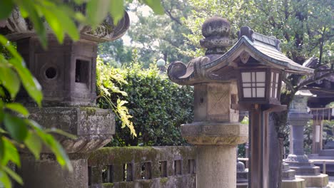 Blick-Auf-Typische-Japanische-Steinsäulen-Im-Japanischen-Tempel-An-Hellen-Und-Sonnigen-Tagen-Mit-Blättern-Im-Vordergrund