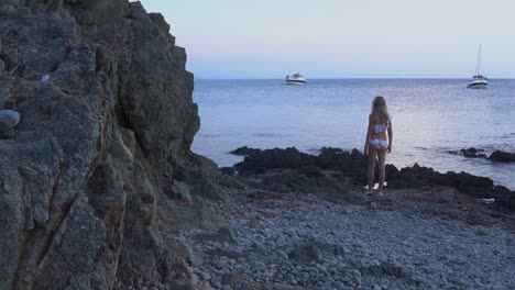 Beautiful-girl-walks-up-to-the-sea-and-throws-a-rock-into-the-water,-and-then-watches-how-it-sinks