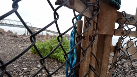 Secured-rusty-gate-chain-link-waterfront-security-fence-on-construction-engineering-site-close-dolly-right