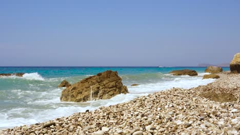 Sea-waves-splashing-on-rocky-shore-with-blue-turquoise-sea-background-in-Ionian-coastline