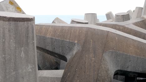 Concrete-formed-coastline-defence-geometric-shape-engineering-on-shoreline-closeup-left-dolly