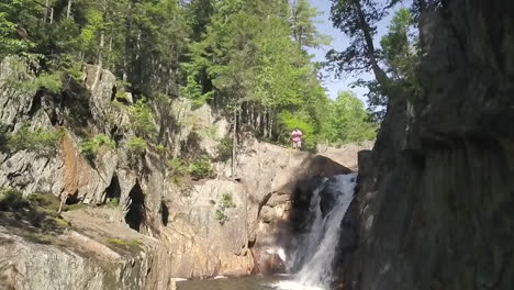 Männlicher-Wanderer,-Der-Neben-Einem-Wasserfall-In-Zeitlupe-An-Kleinen-Wasserfällen-In-Der-Wildnis-Von-Maine-Steht