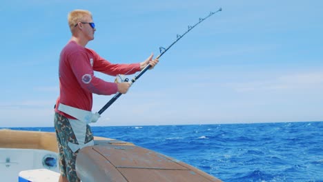 Blond-Caucasian-man-reeling-in-a-fish-from-a-yacht