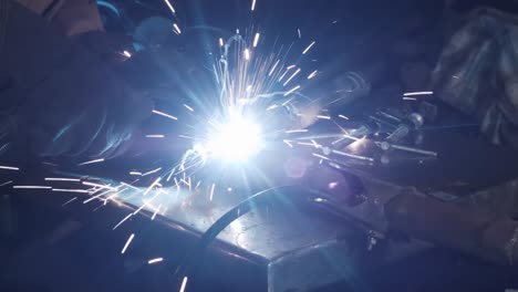 Sparks-as-man-arc-welds-metal-in-garage