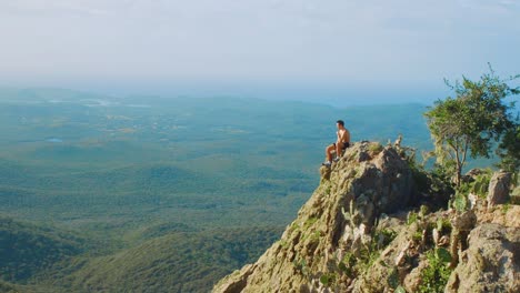 In-this-picture-you-can-see-young-male-person-sitting-on-the-edge-of-the-mountain-cliff