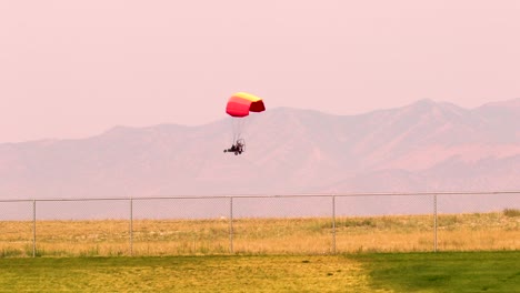 A-motorized-paraglider-crossing-the-sky-at-sunset-with-the-mountains-in-the-background